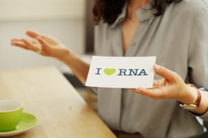 Woman holding a card in front of her with written on it "I love RNA" on it